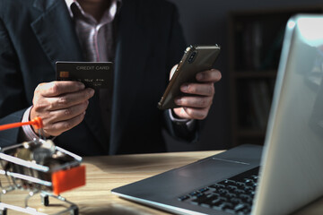 businessman uses a computer laptop and credit card to buy or purchase produce payment online and sits on the chair in the living room at home. The concept of finance and online shopping.