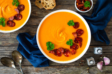 Sweet potatoes cream soup with choriso sausage on wooden background, top view