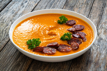 Sweet potatoes cream soup with choriso sausage on wooden background