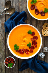 Sweet potatoes cream soup with choriso sausage on wooden background, top view