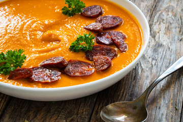 Sweet potatoes cream soup with choriso sausage on wooden background