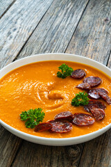 Sweet potatoes cream soup with choriso sausage on wooden background