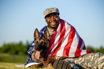Portrait of smiling soldier in uniform hugging his military dog both covered with USA flag. Heroes...