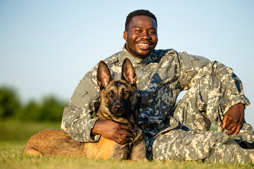 Portrait of smiling soldier and military dog looking straight to the camera.