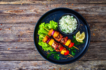 Meat skewers - grilled meat and pineapple with white rice and vegetables on wooden background
