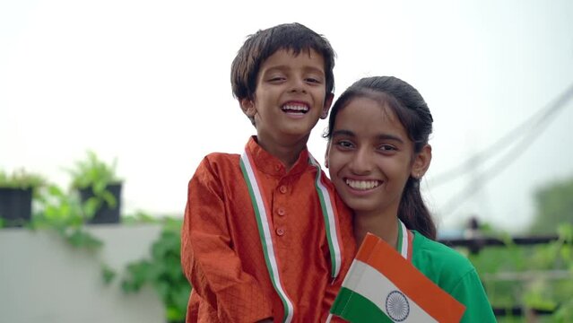 Two Indian Child Celebrating Independence Or Republic Day, Cute Little Indian Child Holding, Waving With Tricolour Flag With Greenery In The Background.