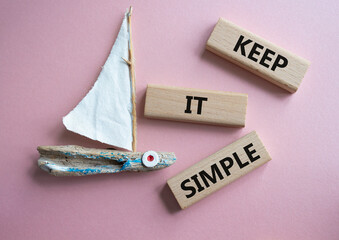 Keep it Simple symbol. Concept words Keep it Simple on wooden blocks. Beautiful pink background...