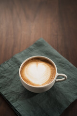 Fresh flat white with latte art in ceramic cup on wood table