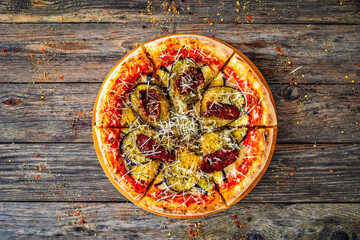 Pizza with eggplant, sun dried tomatoes and parmesan cheese on wooden table
