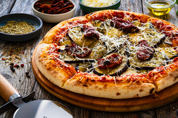Pizza with eggplant, sun dried tomatoes and parmesan cheese on wooden table
