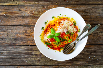 Linguine with tomato sauce, parmesan cheese and basil leaves served on wooden table 