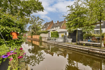 Fototapeta na wymiar a canal in the netherlands with houses and trees on either side, as seen from across the water's edge