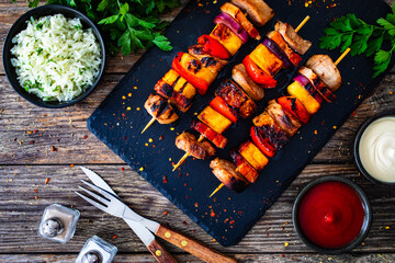 Meat skewers - grilled pork loin, bell pepper and pineapple on wooden background

