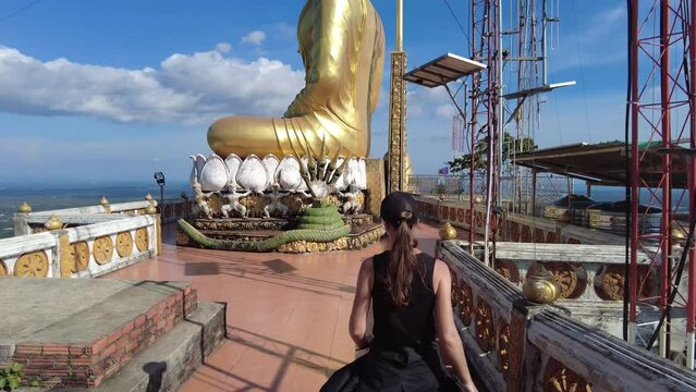 A girl walks along the observation platform at the top of the Temple of the Cave Tiger in the province of Krabi