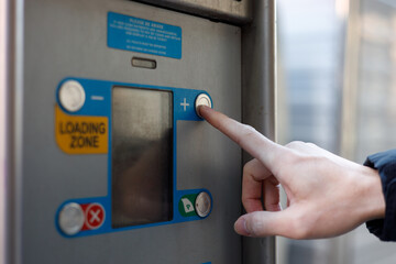 hand pressing city parking card pushing red button to recieve ticket at car parking entrance. Ticket printing terminal machine with wireless card access technology