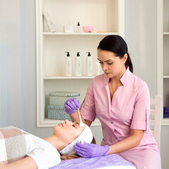 Cosmetologist doing beauty treatment for woman face in spa salon