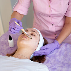 Cosmetologist applying face mask on young women, making beauty treatment in beauty salon