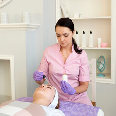 Cosmetologist applying face mask cream on client woman in beauty salon