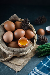 Fresh raw chicken eggs in the basket on dark background. one chicken egg are broken