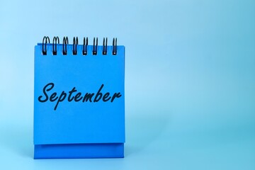 Selective focus of September month desk calendar on blue background with copy space.