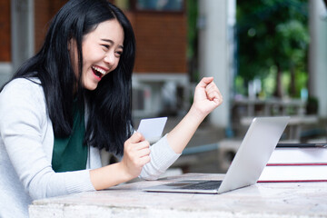 Happy smiling Asian female student holding blank card, concept of student ID card, educational purpose credit card, student loan, scholarship money, educational financial credit