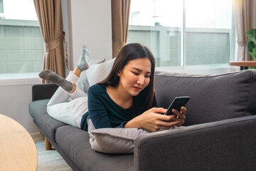 Happy relaxed young woman sitting on the sofa with a mobile phone sitting at home.
