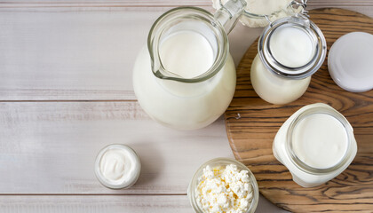 Dairy products in glass jars on light background. Top view, wooden table