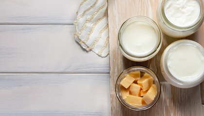 Dairy products in glass jars on light background. Top view, wooden table