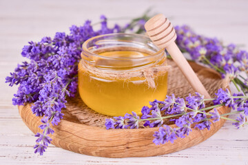 A jar of honey and fresh lavender flowers on a wooden tray.Close-up.
