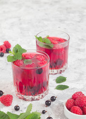 Two glasses with summer drinks with raspberry, black currant and mint. Fresh healthy summer drinks.