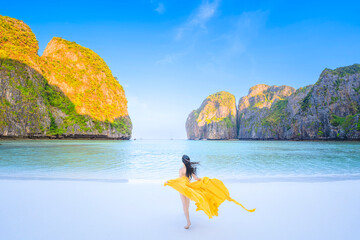 Traveler woman joy fun relaxing on sunny beach surrounded by mountains, Tourist girl on summer holiday vacation trip, beautiful place  at Maya bay, Phi Phi island, Thailand