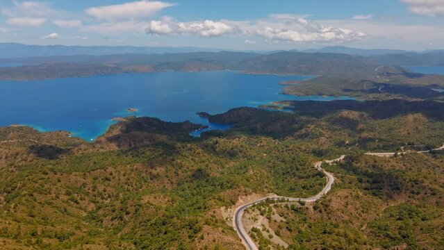 aerial drone footage of beautiful scenic landscape of Marmaris peninsula, mountains and hills with green woods and curved road to Datca destination. peninsula surrounded Aegian and Mediterranean seas.