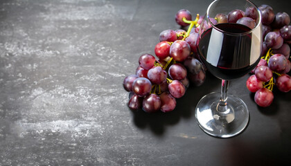 Glass of dry red wine with bunch of purple grapes on dark stone table - Powered by Adobe