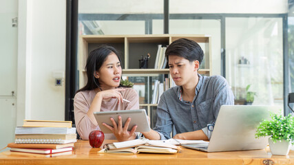 Two Asian students learning together with a laptop and tutor together at cafe