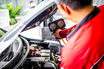 Car mechanic or serviceman refilling air condition and checking a air compressor for fix and repair...