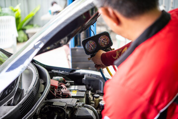 Car mechanic or serviceman refilling air condition and checking a air compressor for fix and repair problem at car garage or repair shop