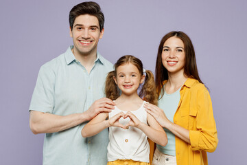 Young parents mom dad with child kid daughter girl 6 year old wear blue yellow casual clothes show shape heart with hands heart-shape sign, hug isolated on plain purple background Family day concept