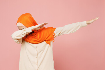 Young arabian asian muslim woman wear orange abaya hijab doing dab hip hop dance hands move gesture...