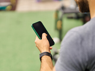 Portrait of a young black man using a phone and texting taking a break exercising in a gym, having a training workout in gym, healthy lifestyle and cardio exercise at fitness club concepts