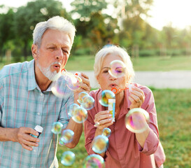 woman man senior couple  together elderly active happy retirement bubble soap blowing fun blow...