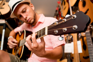 Young musician tuning a classical guitar in a guitar shop