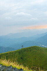 The breathtaking view in Kanchanaburi, Thailand, as seen from the point of view of a tourist,  being surrounded by mountains and a golden sky in the background.