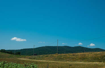 Fototapeta na wymiar landscape, good weather, blue sky, power lines in the field and green mountains on the backgrounds