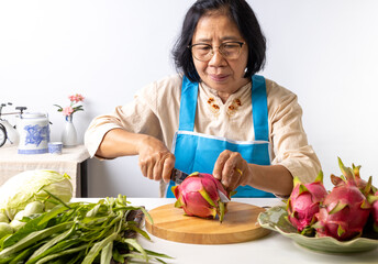 Asian senior woman slicing dragon fruit in the kitchen