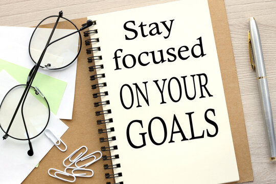 Stay focused on your goals. open notebook with stickers and glasses .word on page