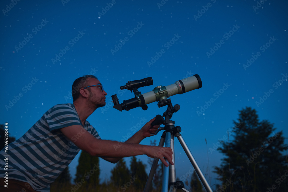 Wall mural astronomer looking at the starry skies with a telescope.
