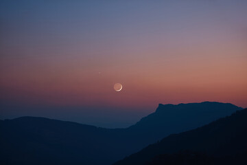 Silhouette of a countryside with Milky Way stars, planets and crescent Moon.