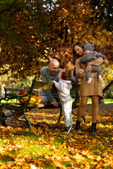 A family with two children on a walk in the park in autumn