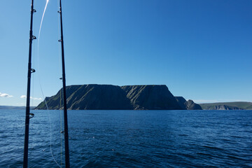 The northernmost tip of Europe large and dramatic rock cliff of North Cape and two fishing rods on summer day on Mageroya island in Finnmark in Northern Norway.