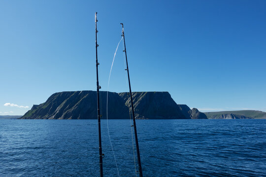 The northernmost tip of Europe large and dramatic rock cliff of North Cape and two fishing rods on summer day on Mageroya island in Finnmark in Northern Norway.
